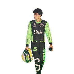 Gabriel Bortoleto walking in the pit lane holding helmet during the 2025 season in his full F1 suit, ready for race action.
