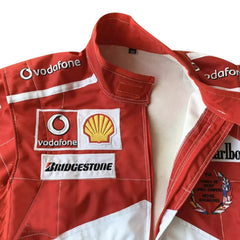 Close-up of the 2005 Schumacher suit highlighting fine embroidery, Ferrari red color tone, and precise stitching on race-worn sponsor badges.Bestracewear