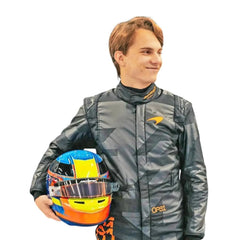 Close-up of Piastri holding custom-designed helmets — Piastri with a high-gloss blue-yellow-red helmet—contrasting the matte black suit- Best racewear