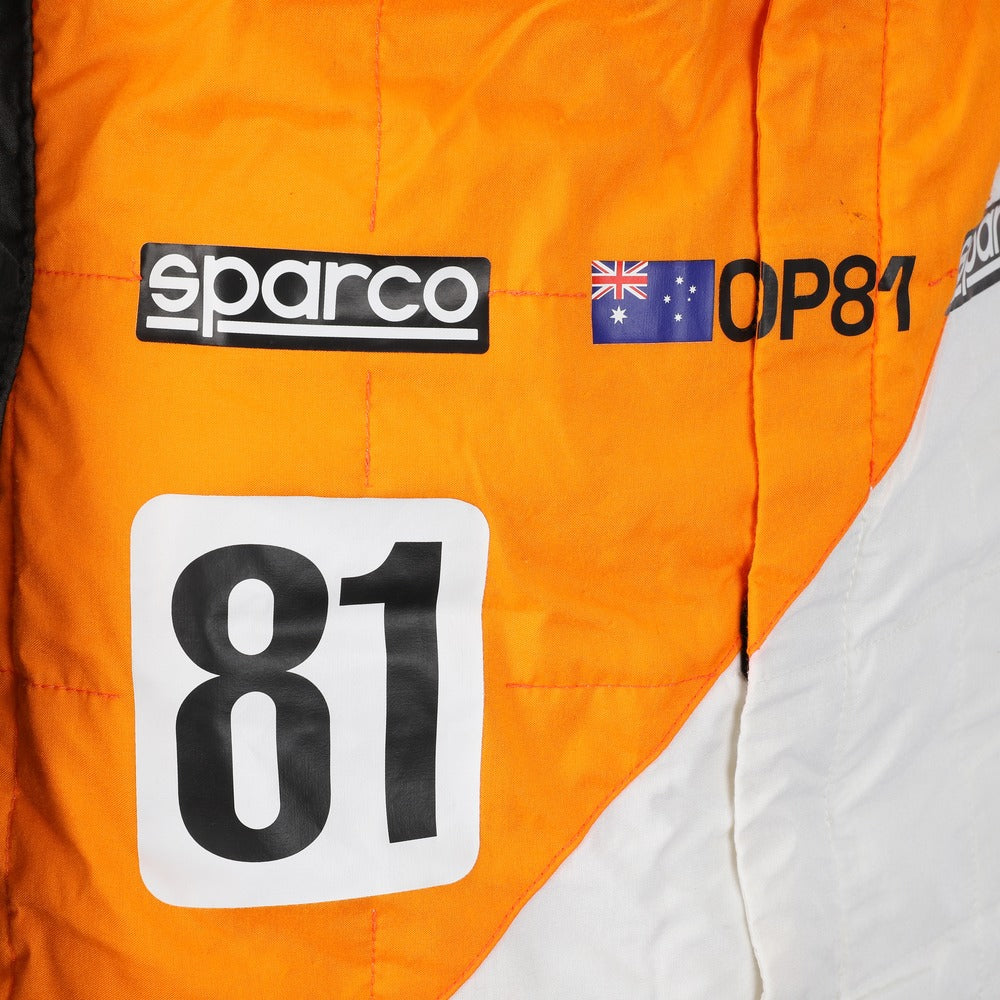 Close-up of Oscar Piastri’s 2023 Spanish GP race suit, emphasizing high-resolution logos, stitch detailing, and special edition ‘Triple Crown’ patchwork.Bestracewear